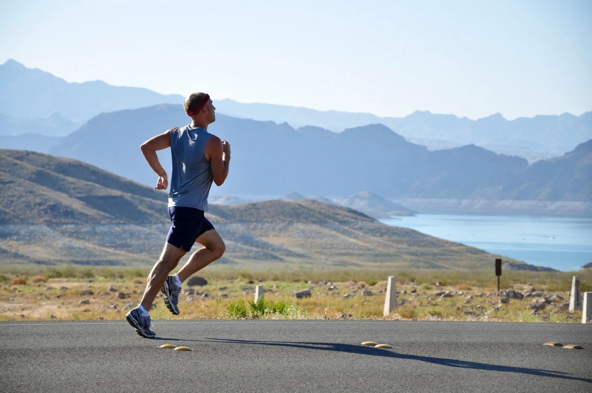 Man running on road with mountains in the background