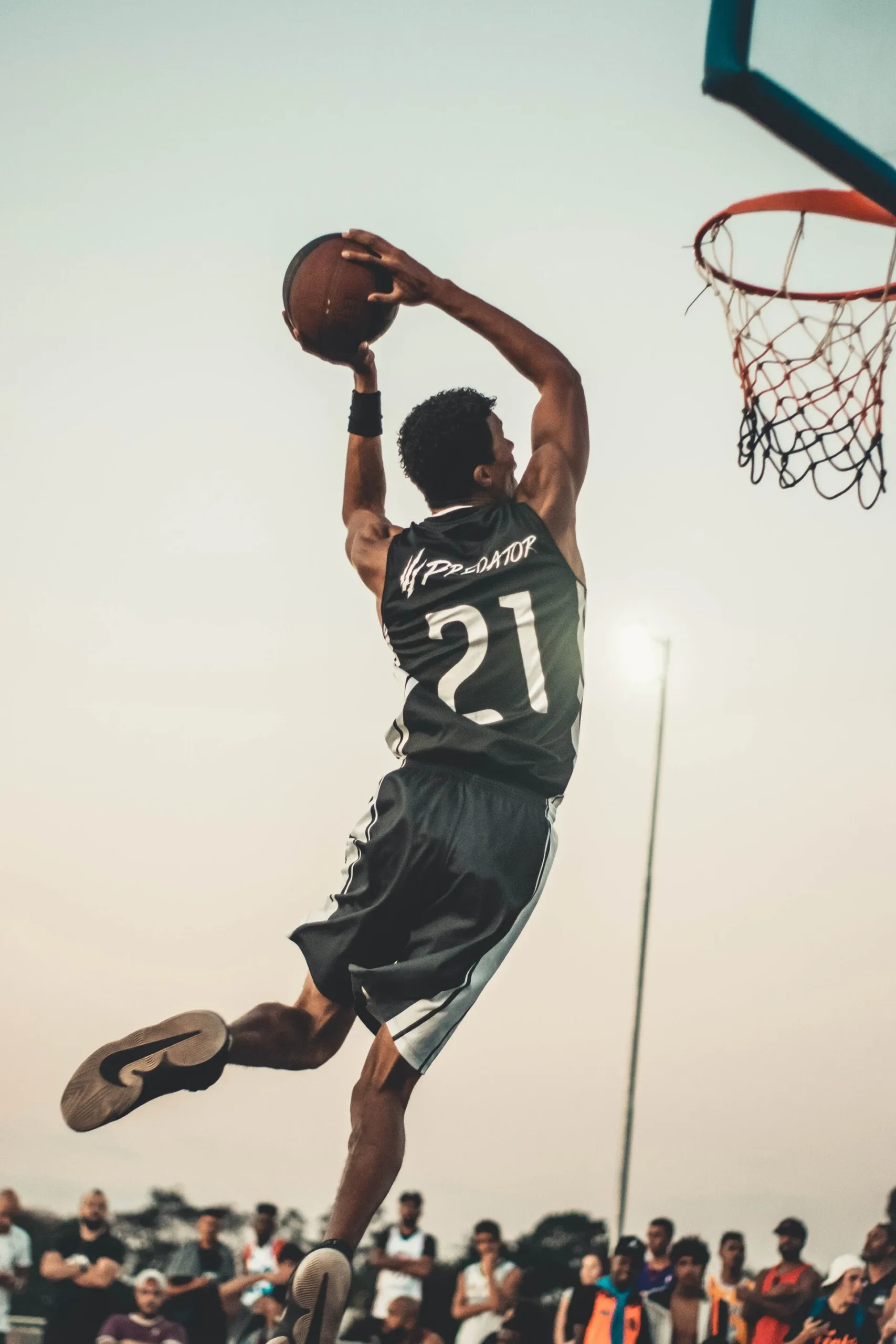 Man in mid-air dunking a basketball into a basketball goal