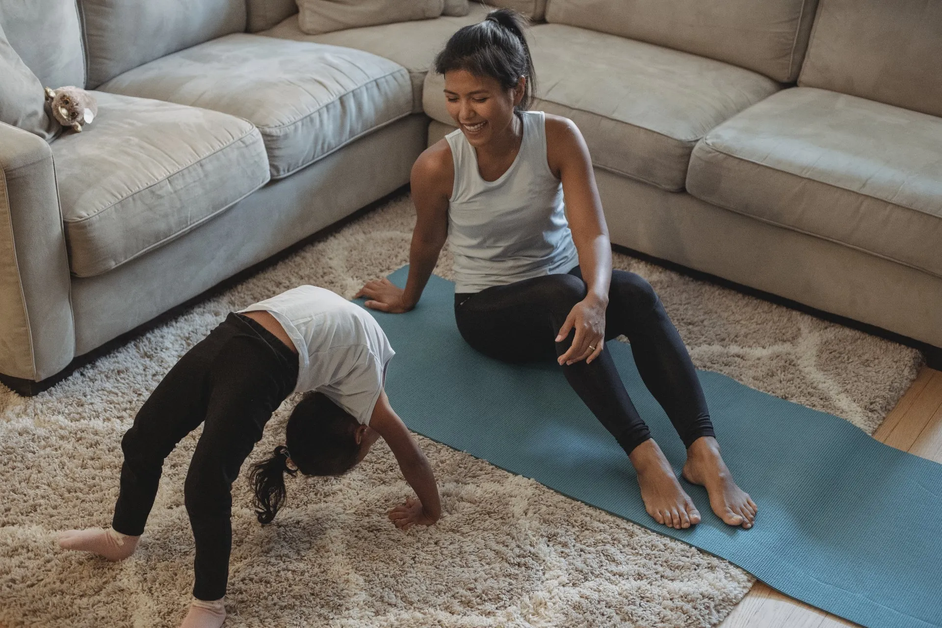 Mother and daughter performing yoga moves in living room