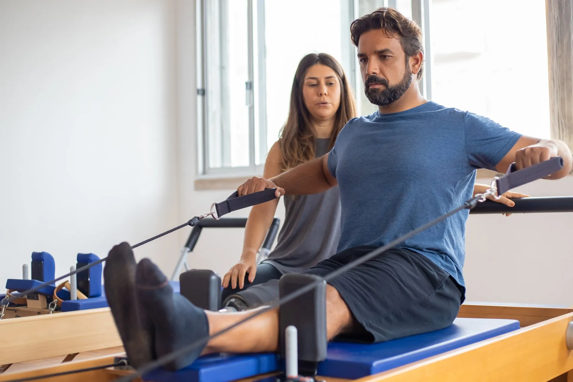 Man performing exercises with a women in the background seeming to coach.