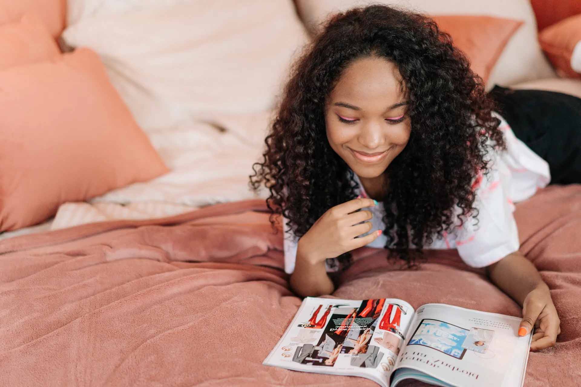 Young woman smiling while laying down reading magazine