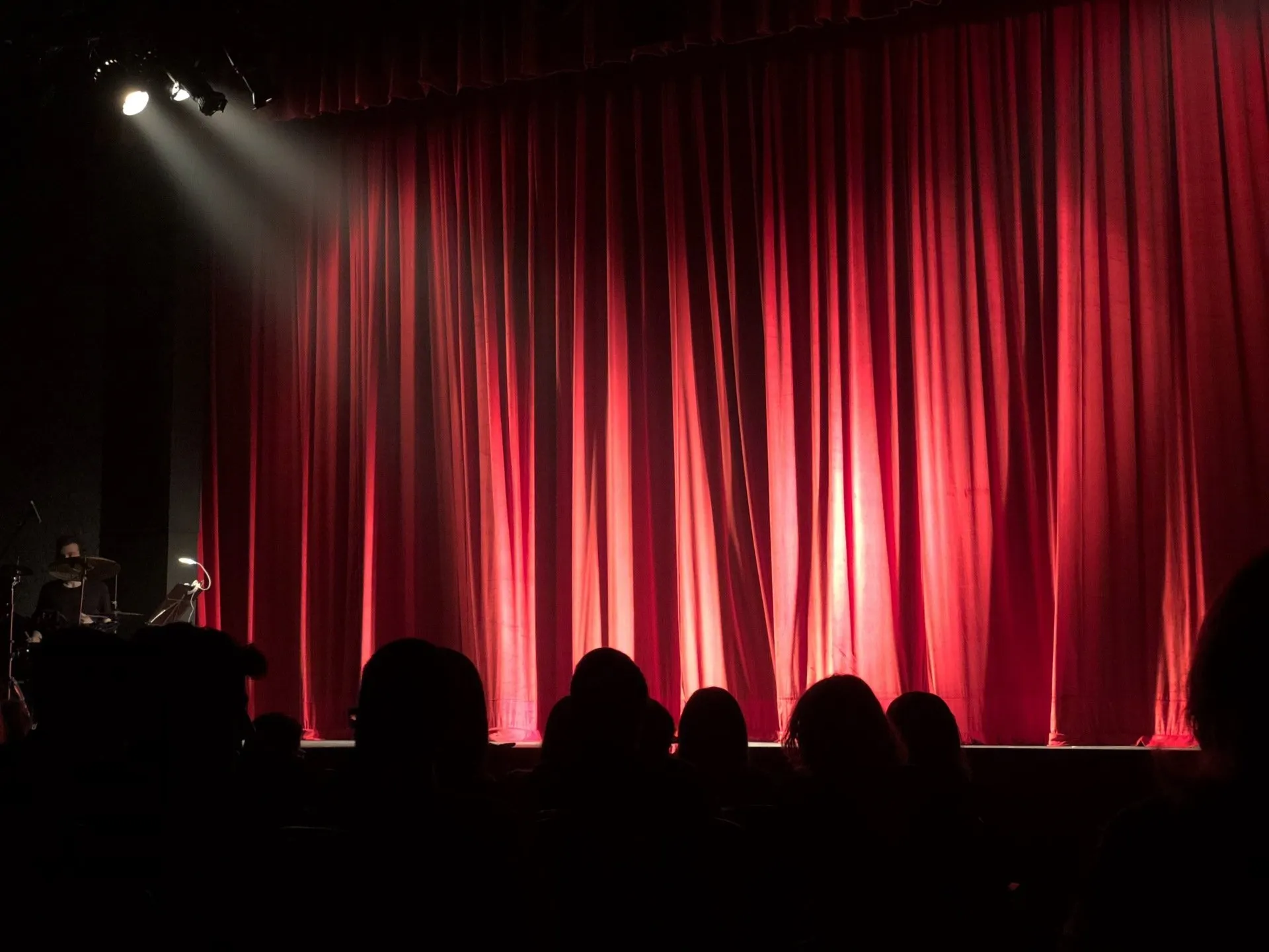 Audience silhouette sitting in front of a red stage curtain