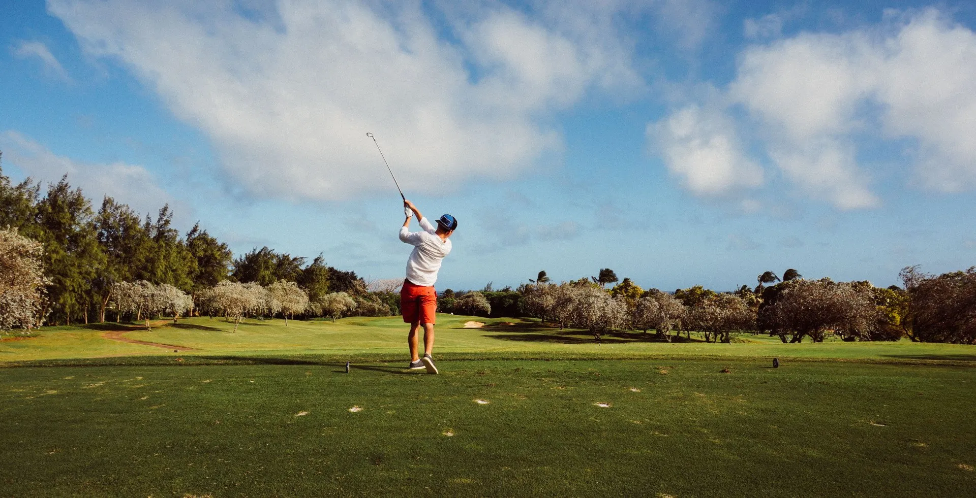 Man swinging golf club on a tee box at a golf course